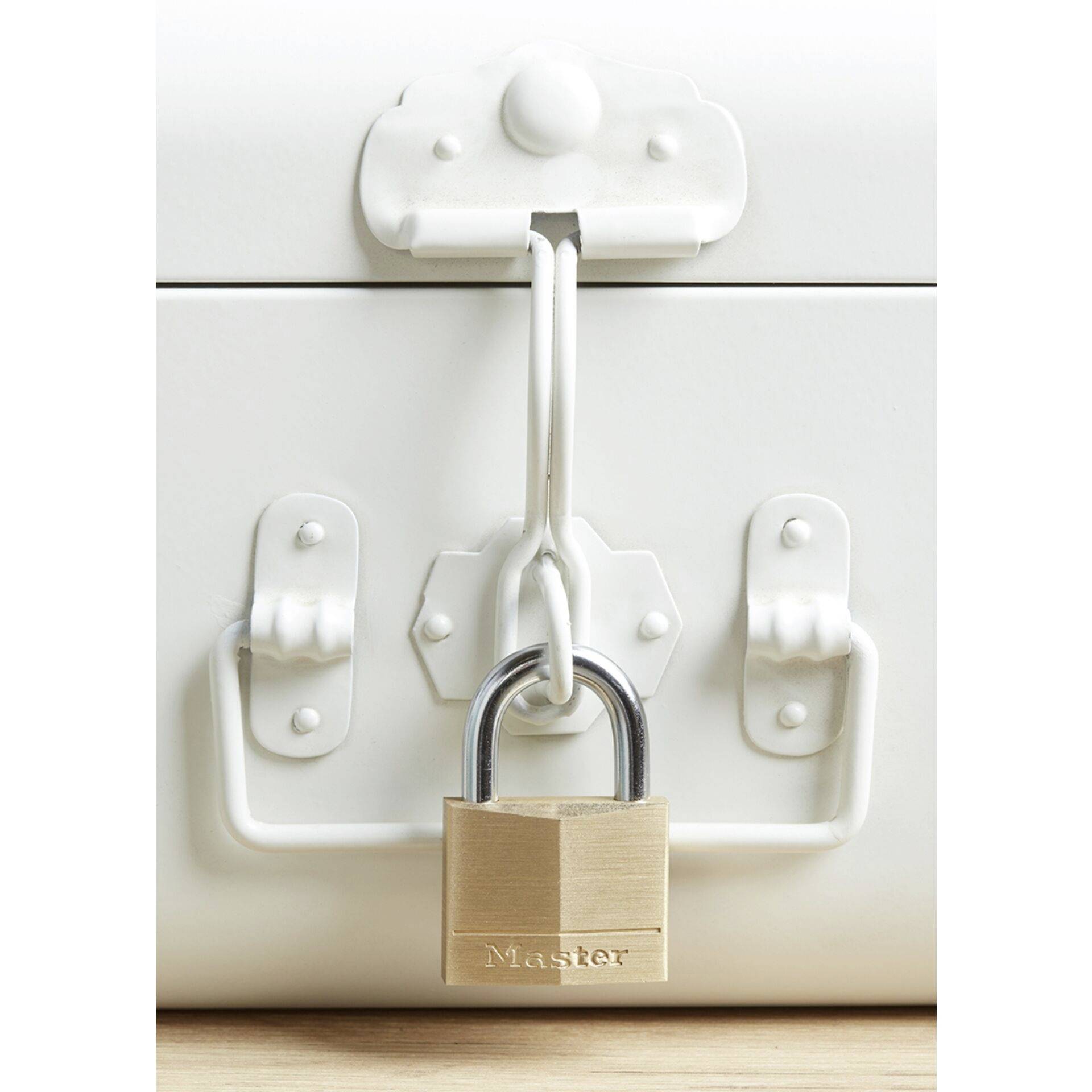 Une valise métallique blanche fermée par un cadenas, posée sur une surface en bois. Le cadenas porte l'inscription 'Master'.