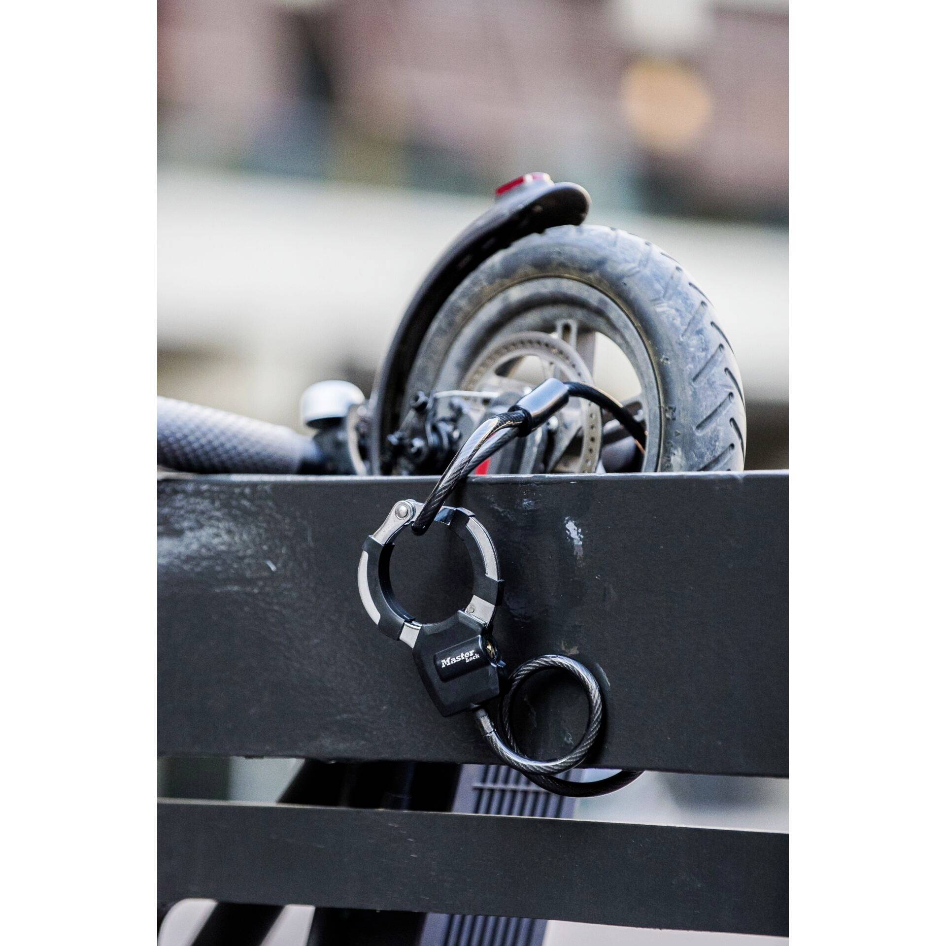 Un vélo est sécurisé avec un cadenas contre une rambarde. La roue arrière est au premier plan, le cadenas protège contre le vol.