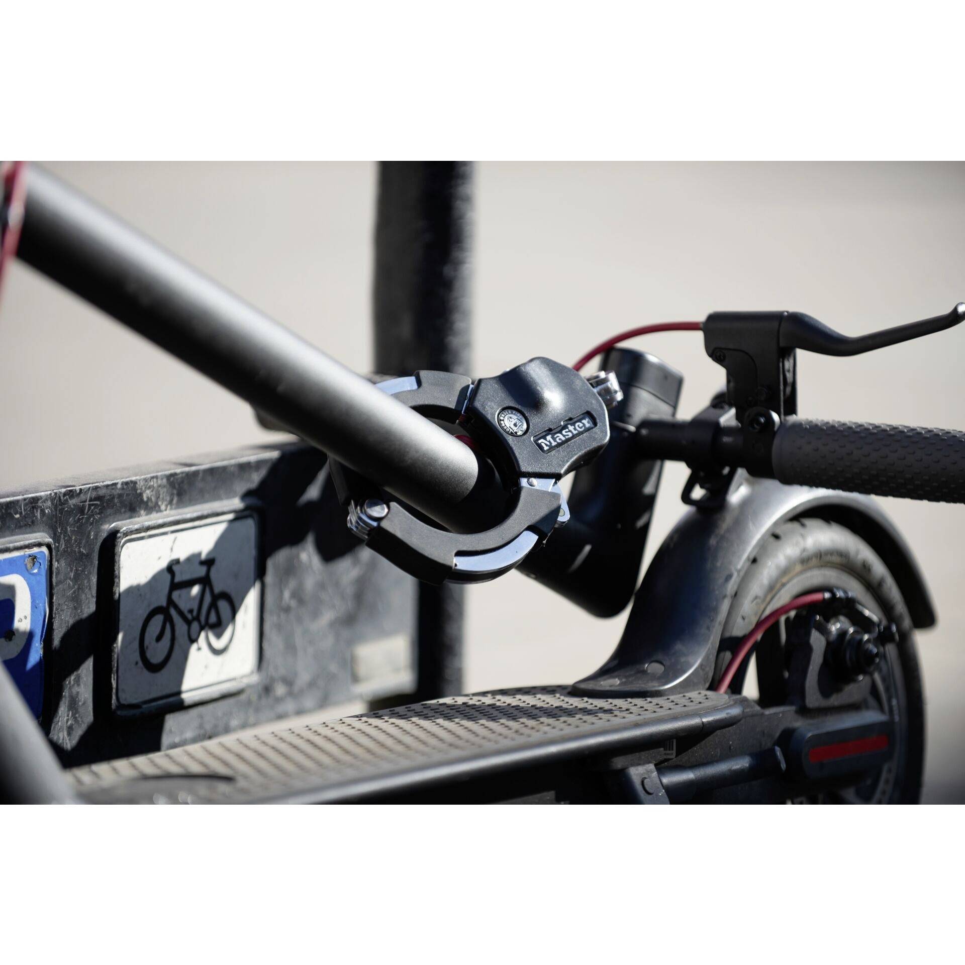 Gros plan sur un emplacement de stationnement pour vélos avec une boucle métallique permettant d'attacher les vélos. En arrière-plan, un pictogramme de vélo est visible sur un panneau.