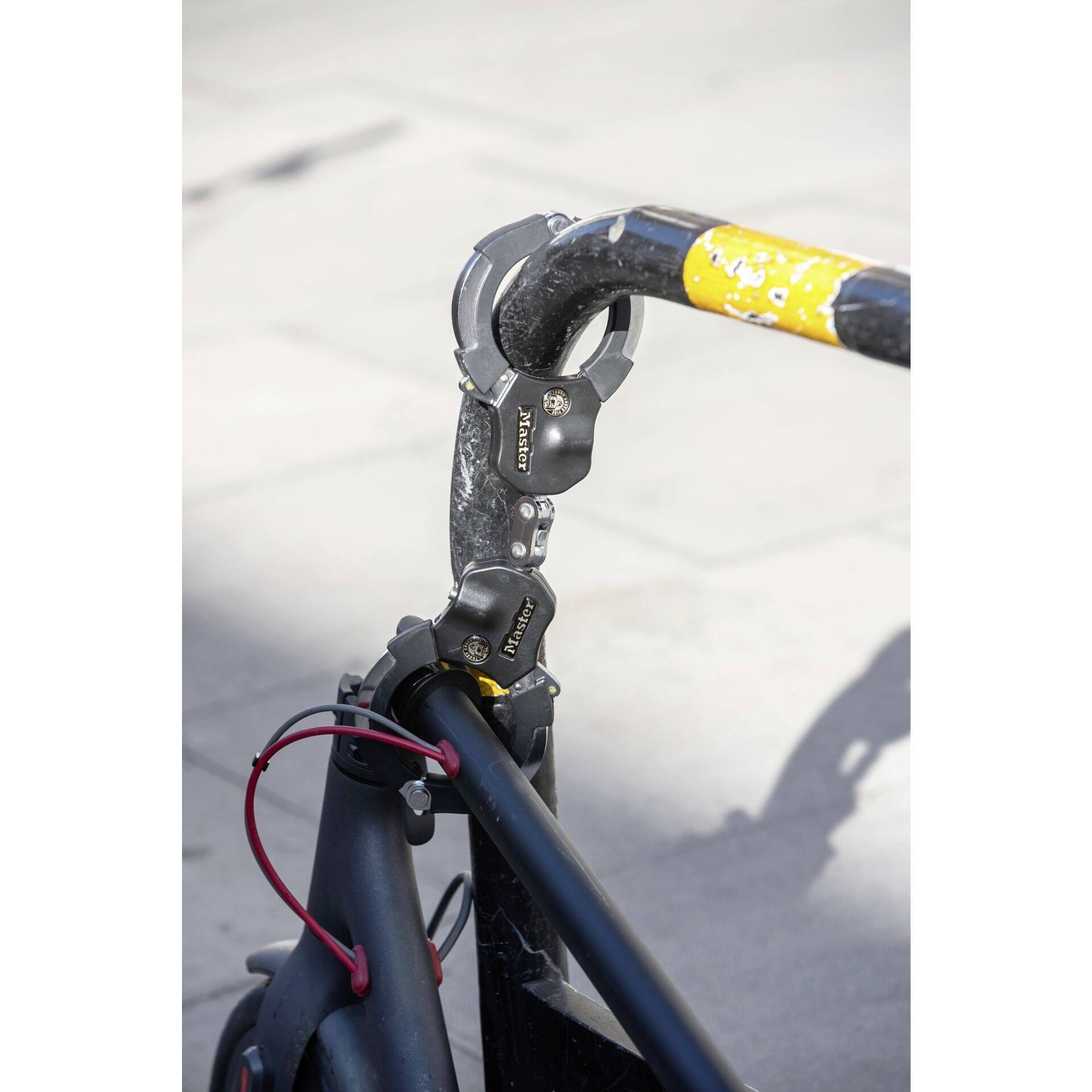 Un vélo sécurisé par un antivol noir et jaune sur une rambarde fixe.