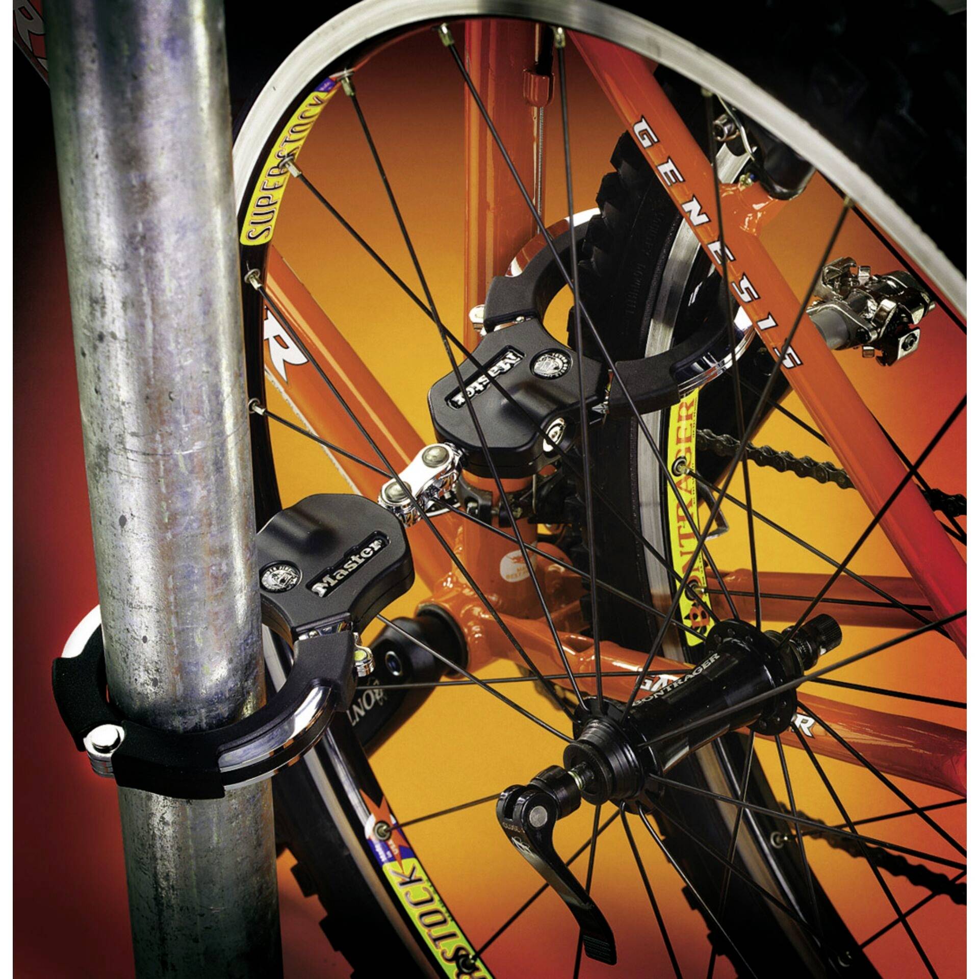 Un vélo sécurisé par deux cadenas est attaché à un poteau métallique. Le vélo est orange et présente des pneus robustes.