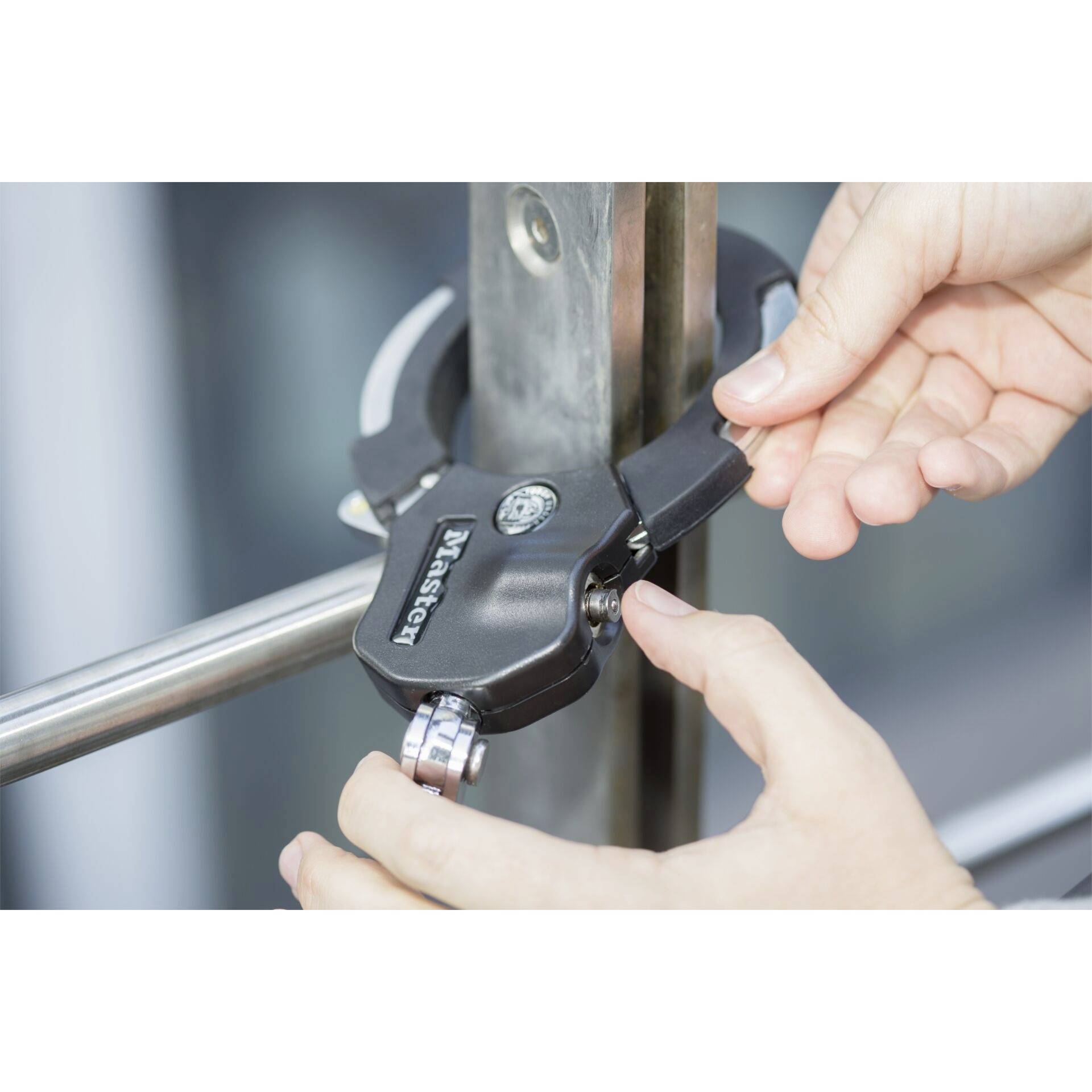 Des mains referment un cadenas autour d'une barre métallique.