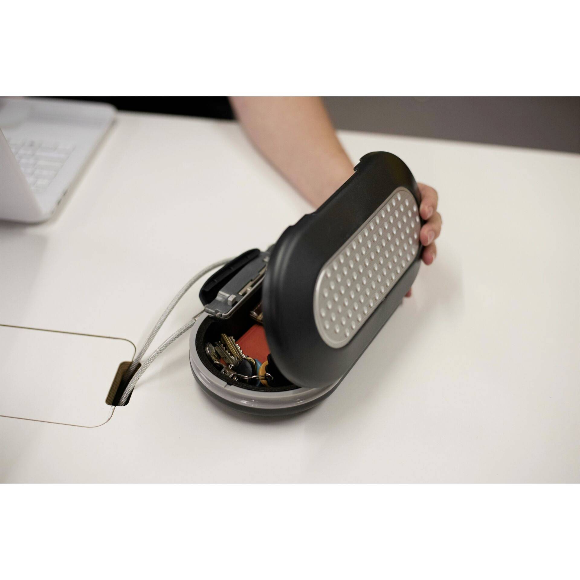 Une personne montre une mallette portative ouverte contenant divers composants électroniques sur une table.