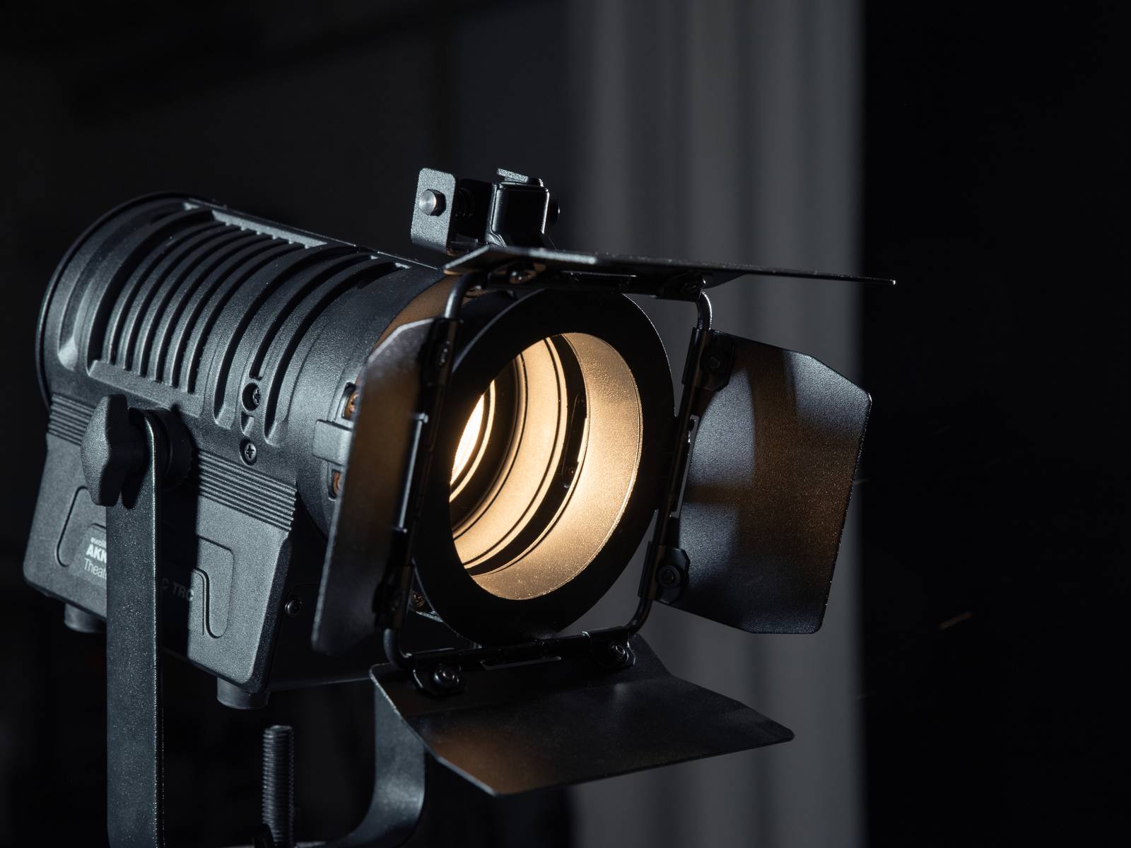 Un projecteur émet de la lumière. C'est un éclairage de scène professionnel avec des volets noirs pour contrôler le faisceau lumineux.