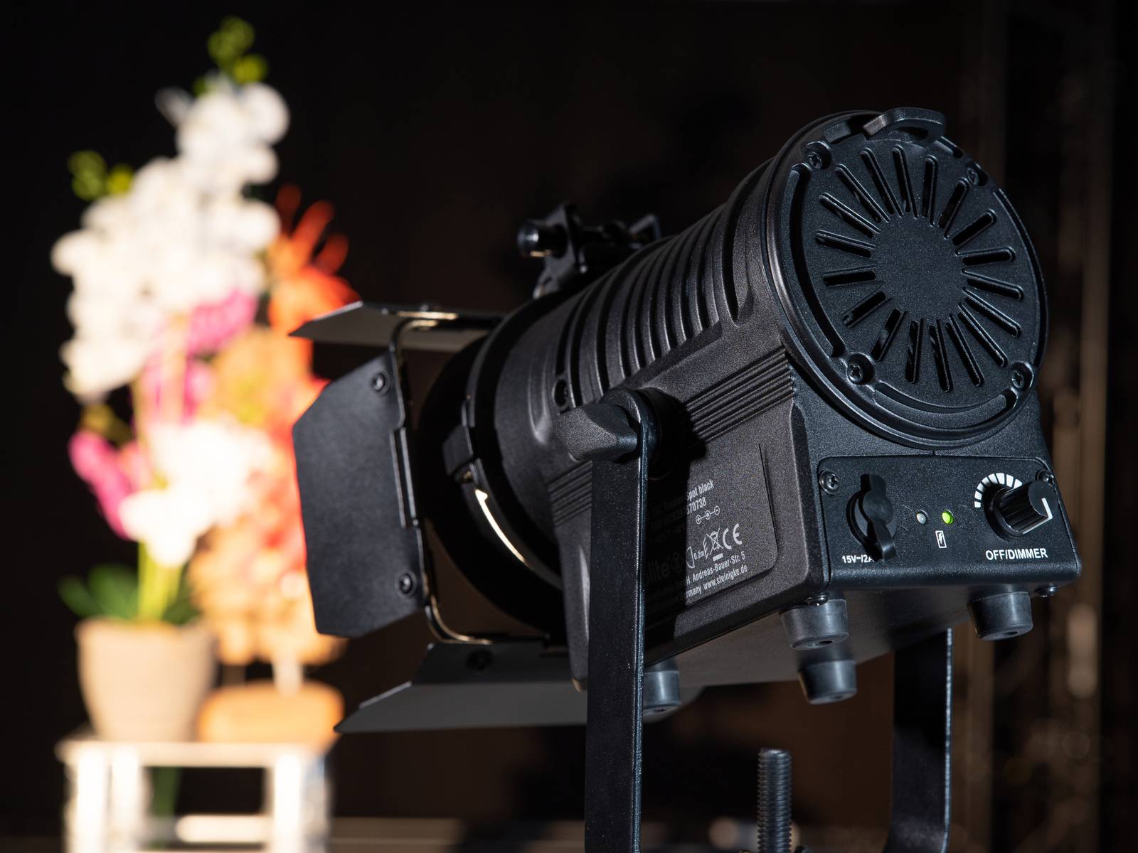 Un projecteur est braqué sur un arrière-plan flou avec un bouquet de fleurs. L'accent est mis sur l'équipement technique.