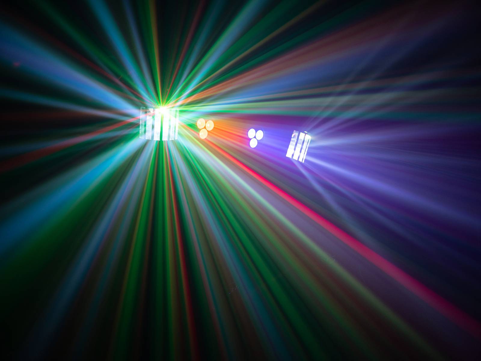 Des rayons lumineux colorés divergent dans différentes directions, créant un motif kaléidoscopique sur un fond sombre.