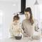 Une femme et son enfant font de la pâtisserie ensemble dans une cuisine lumineuse. Tous deux sourient et l'enfant remplit un bol d'ingrédients.
