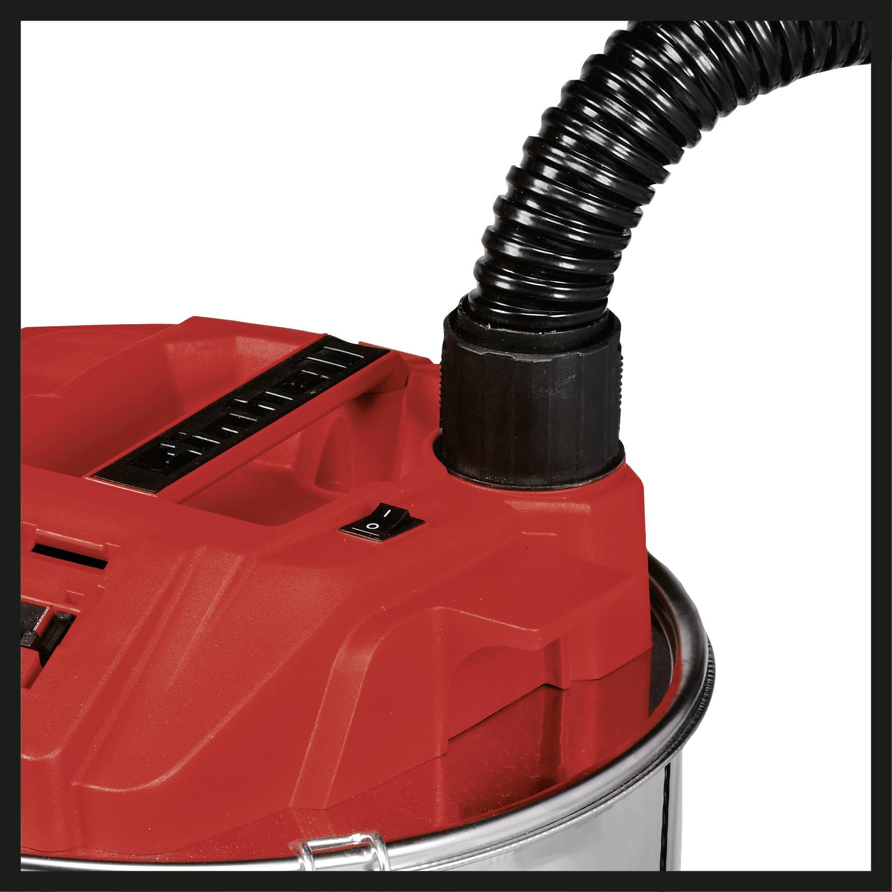 Un aspirateur industriel rouge avec un tuyau noir est fixé sur une base métallique, prêt à nettoyer de grandes surfaces.