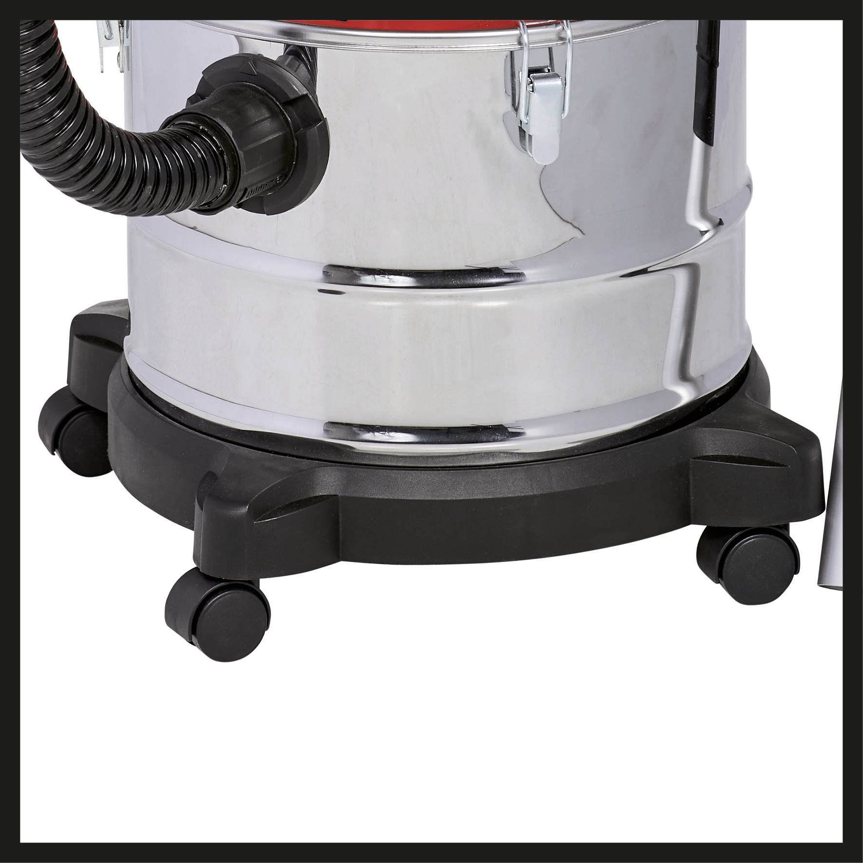 Aspirateur avec un réservoir cylindrique métallique monté sur roulettes, un tuyau noir sur le côté et une base noire à la base.