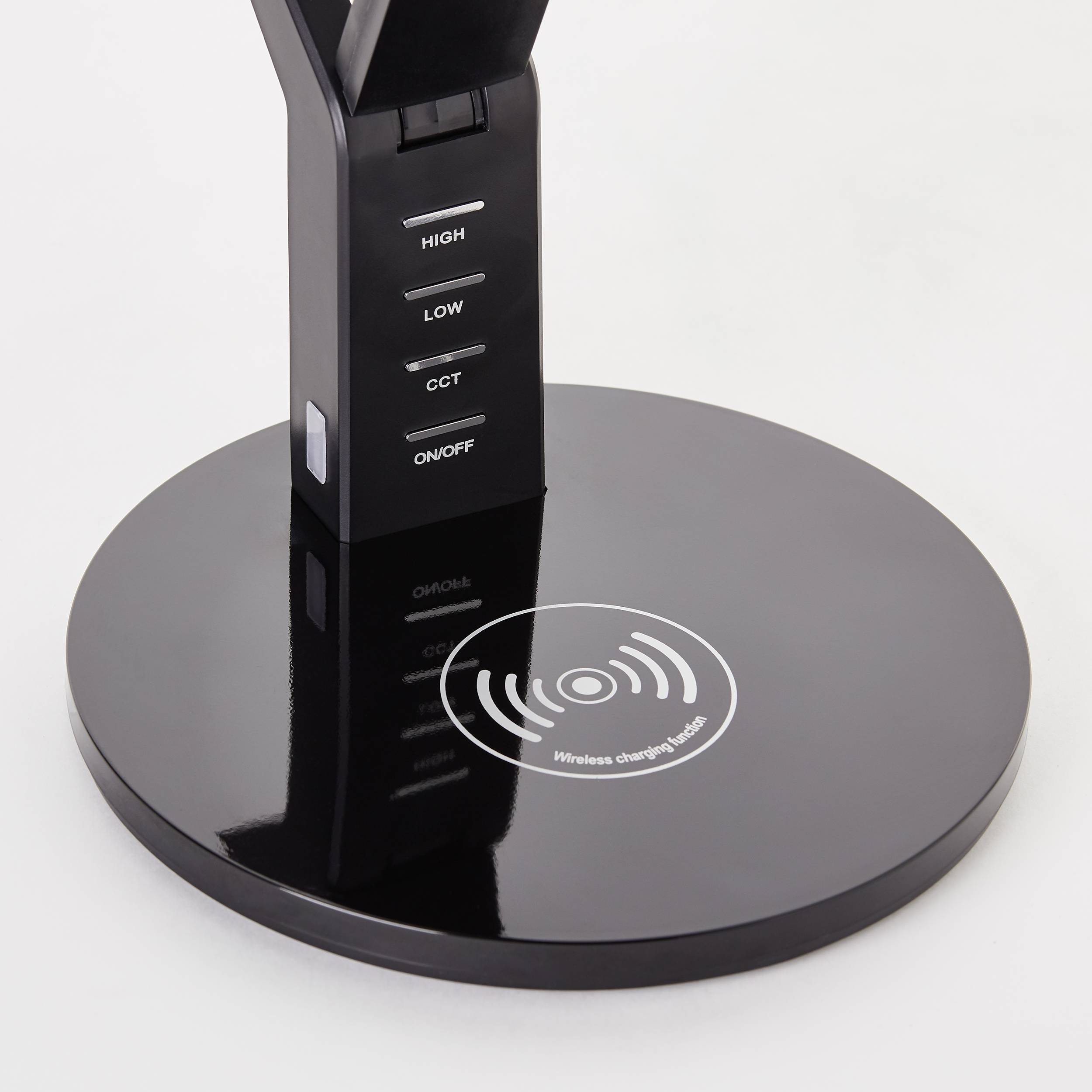 Une lampe de table noire avec fonction de chargement sans fil à la base, comportant des touches 'High', 'Low', 'CCT' et 'On/Off' sur le socle.