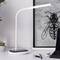 Un bureau élégant avec une lampe qui permet de charger un téléphone sans fil. À côté se trouve une œuvre d'art présentant un motif d'insecte géométrique en arrière-plan.