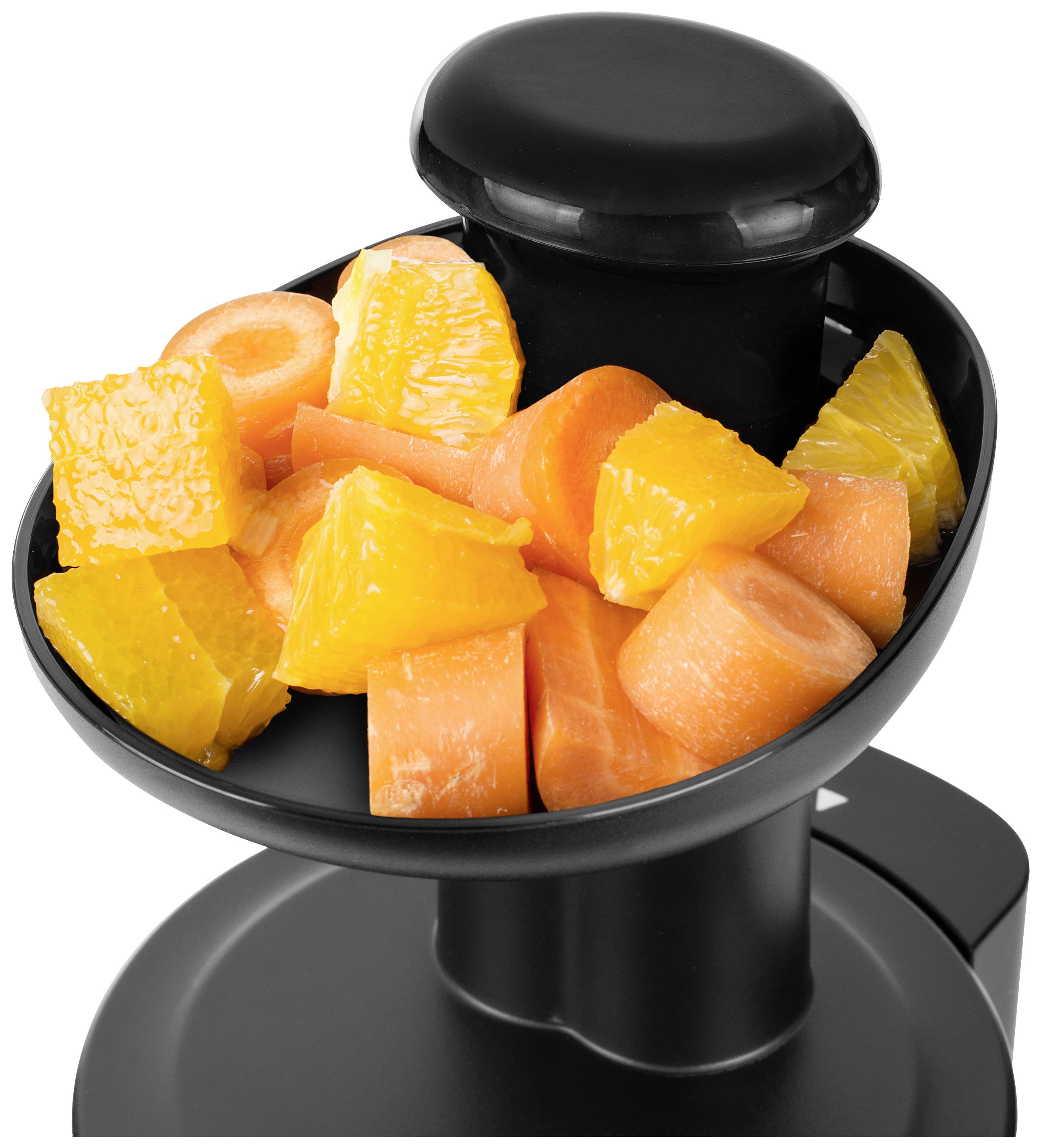 Bol avec des morceaux d'oranges coupés et des tranches de carottes sur un extracteur de jus.