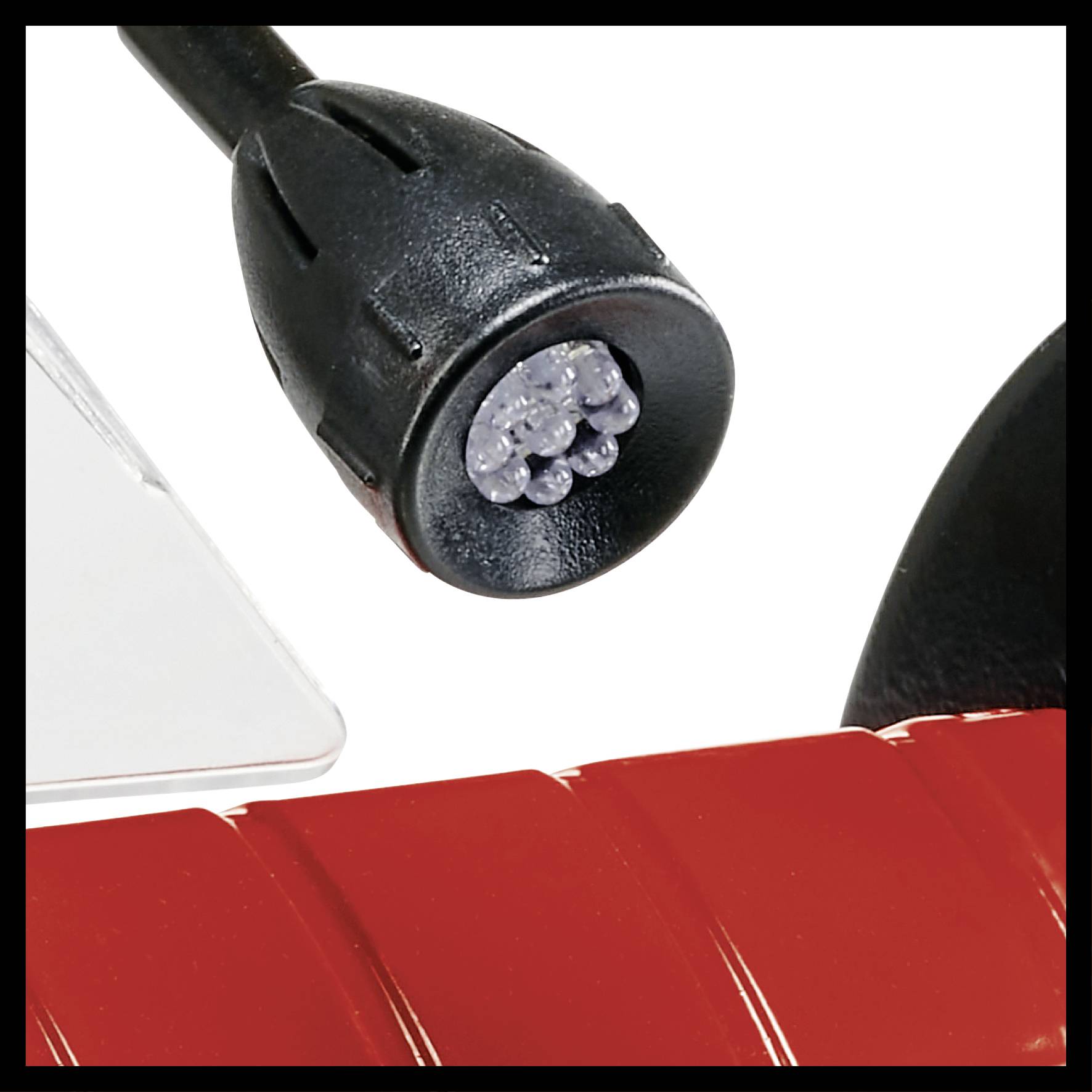 Gros plan sur une connexion de câble noir avec plusieurs broches argentées, insérée dans un appareil rouge et blanc.