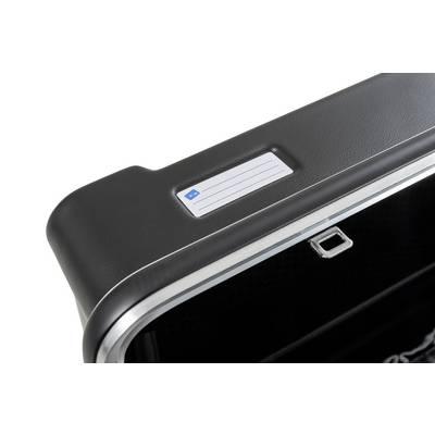 Une valise noire avec une étiquette blanche sur le dessus. La valise a un bord argenté et une petite fermeture.