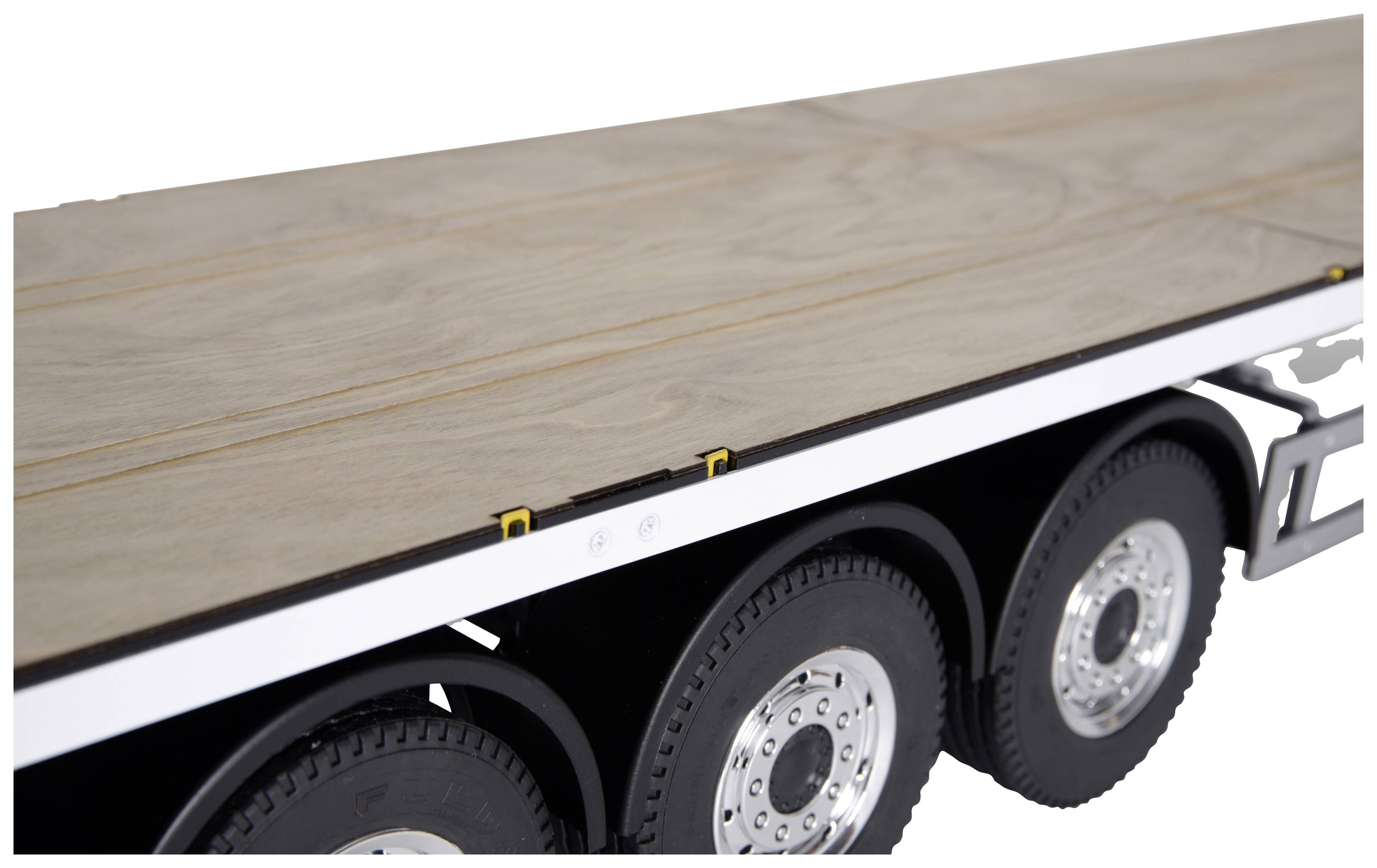 Un remorque à trois essieux, plate et équipée d'une plateforme en bois, adaptée au transport de charges lourdes sur route.