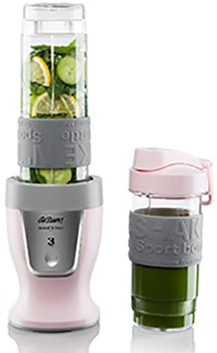 Un mixeur rose sur socle avec une manchette grise contient des ingrédients de smoothie vert. À côté se trouve un gobelet à shake avec un smoothie vert prêt à être consommé.