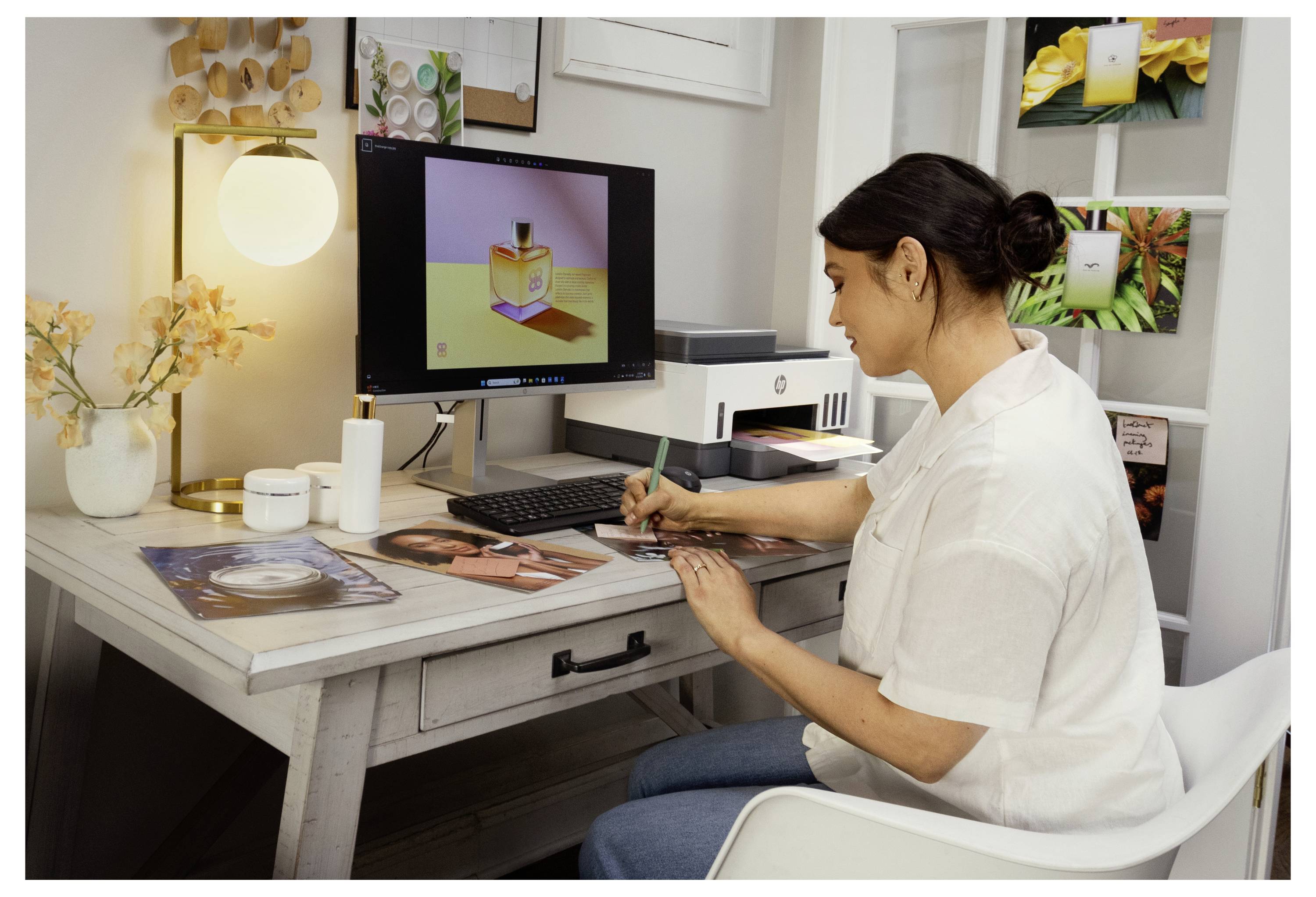 Designer esquissant des maquettes d'emballage à un bureau, utilisant un ordinateur pour examiner une conception de produit à l'écran