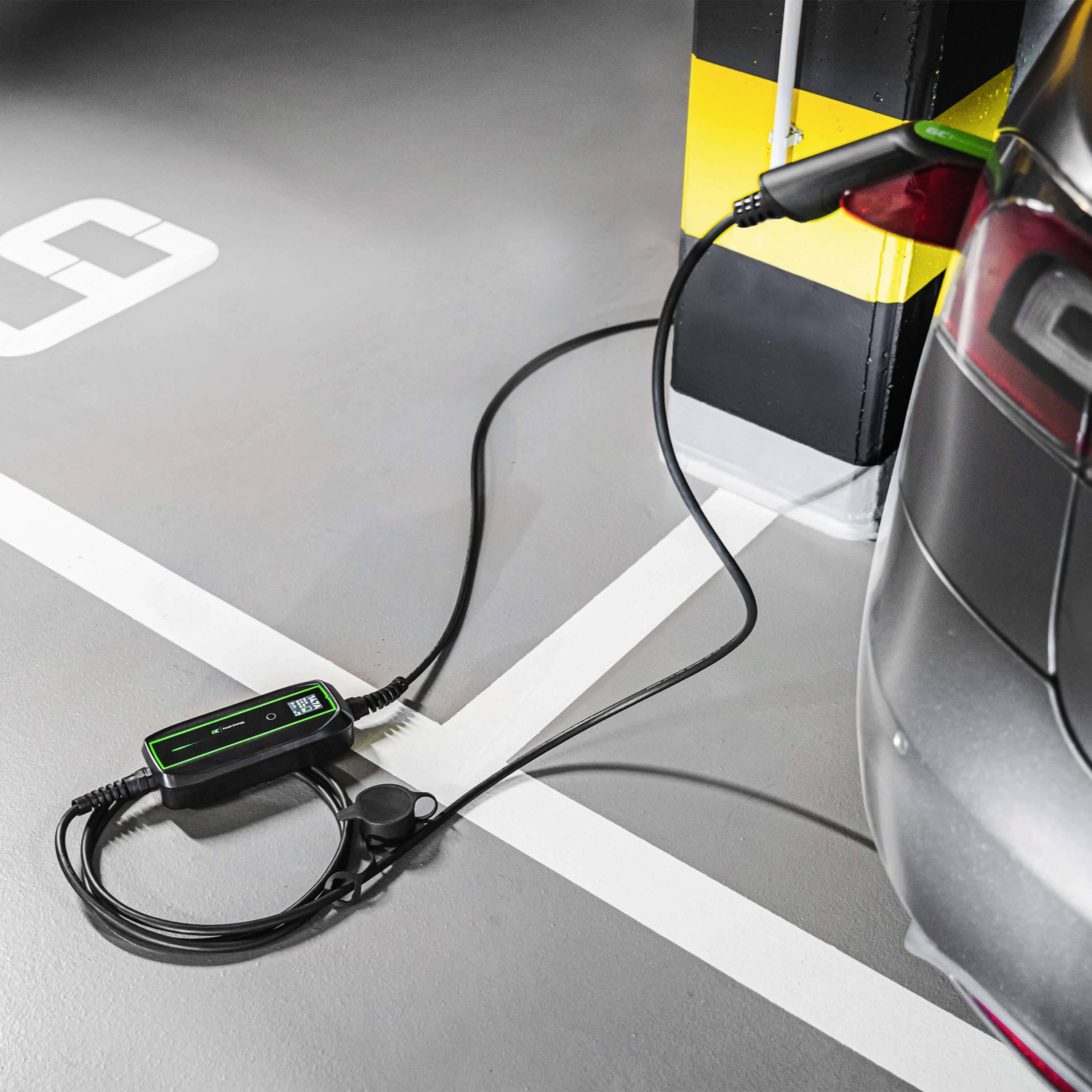 Une voiture électrique est en charge dans un garage, branchée à une borne de recharge. Un câble relie la voiture à la borne de chargement sur un poteau marqué en jaune et noir.