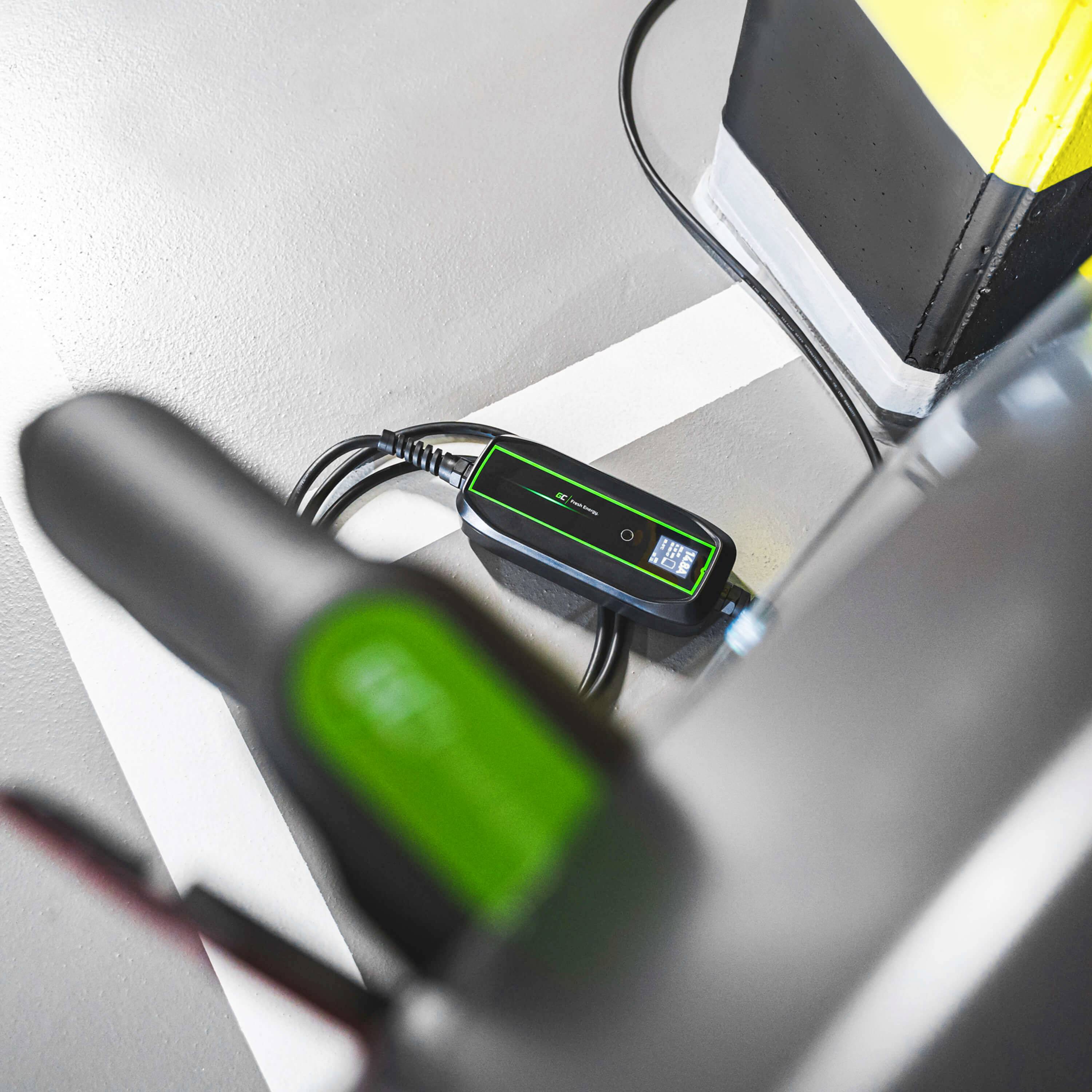 Un système de charge électrique est connecté à un véhicule électrique. Vue rapprochée du chargeur sur un sol gris à côté d'une voiture garée.
