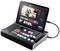 Une console de mixage avec une tablette connectée affiche un logiciel de production vidéo avec plusieurs panneaux de contrôle et des aperçus à l'écran.