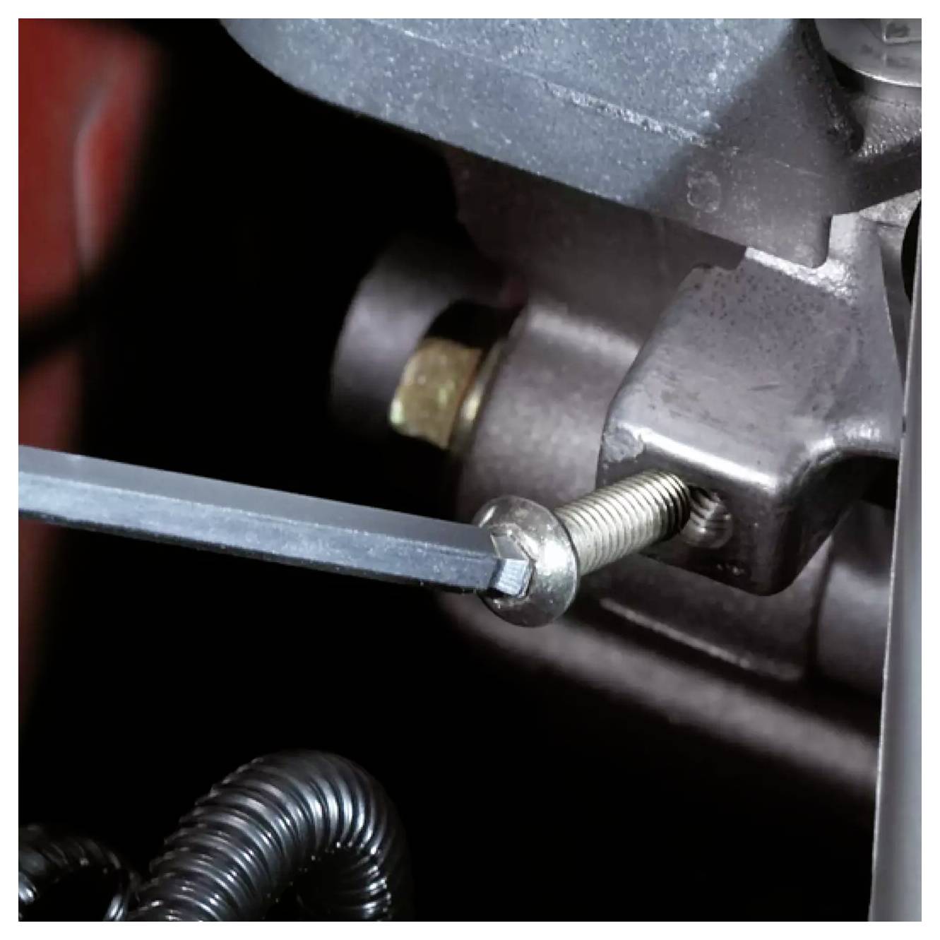 Un gros plan d'un composant moteur avec un outil manuel ajustant un boulon, illustrant une maintenance ou une réparation en cours.