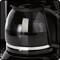 Un distributeur de café noir avec une carafe en verre remplie de café fraîchement brassé. La carafe reflète la lumière.