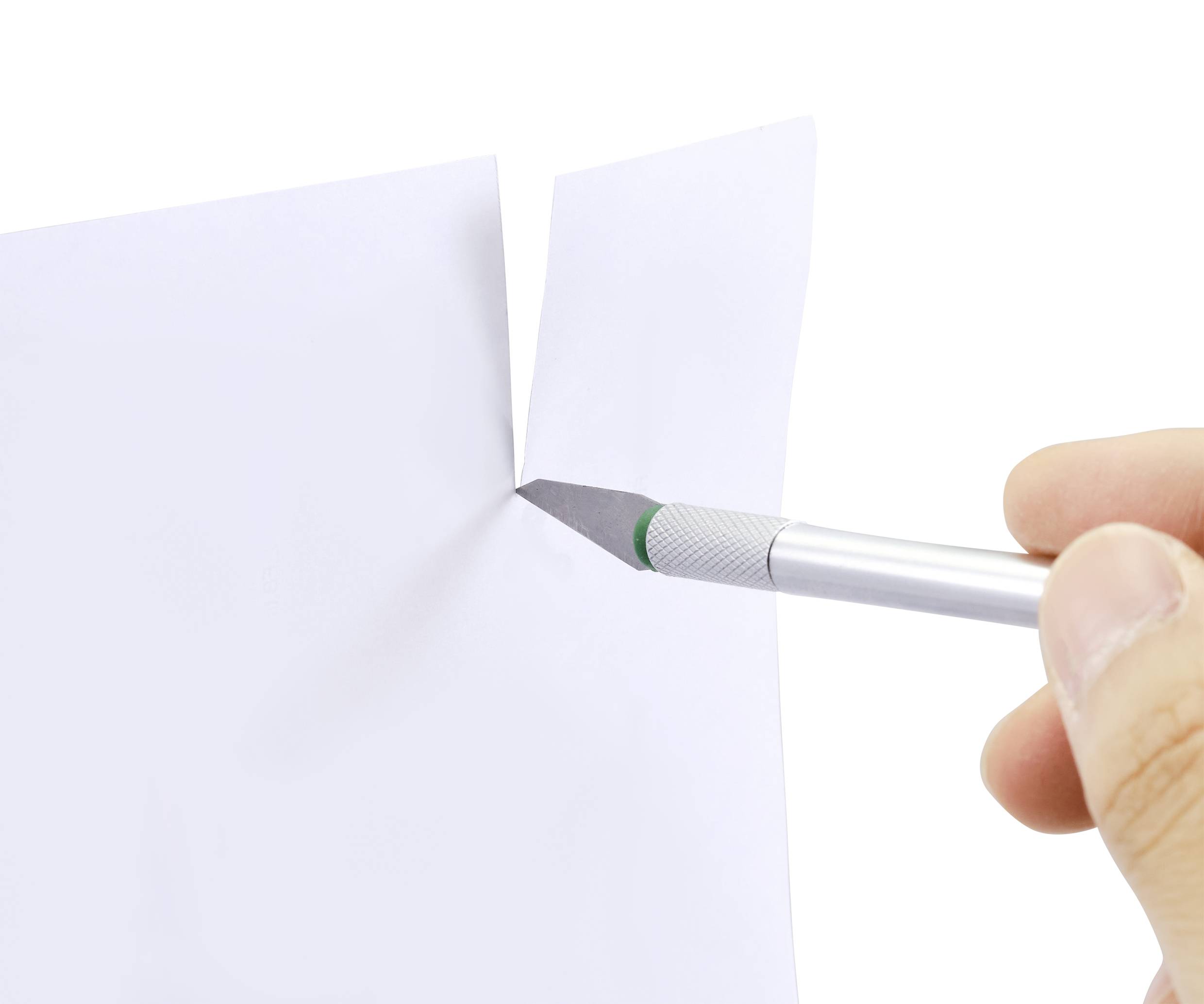 Une main tient un scalpel et coupe un morceau de papier blanc.