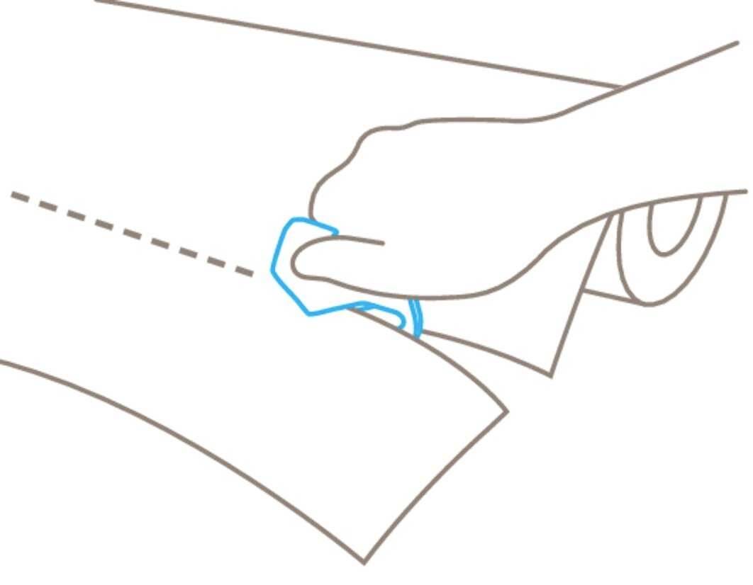 Une main coupe du papier le long d'une ligne pointillée à l'aide d'un outil de coupe bleu qui facilite l'opération.