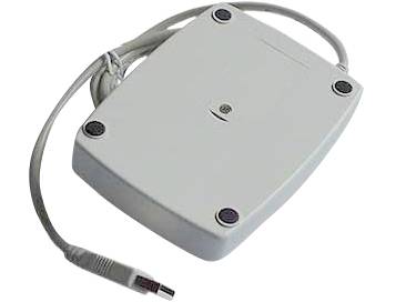 Adaptateur électronique gris, rectangulaire, doté d'un câble et d'un connecteur. Possède quatre tampons en caoutchouc noir sur sa face inférieure.
