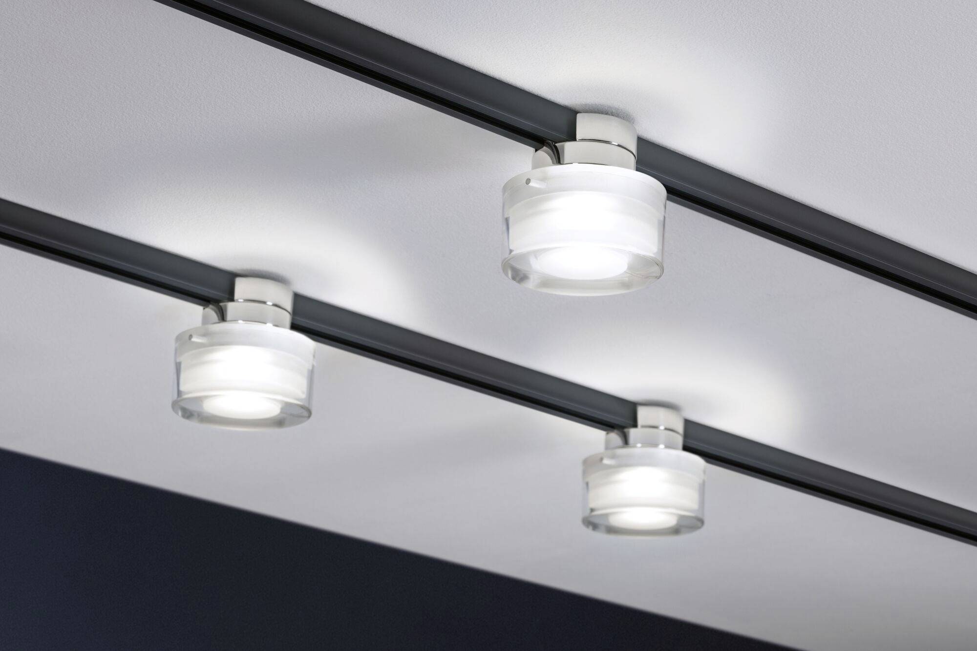 Trois lampes de rail modernes au plafond avec lumière allumée, éclairage idéal pour des espaces de vente ou d'exposition.