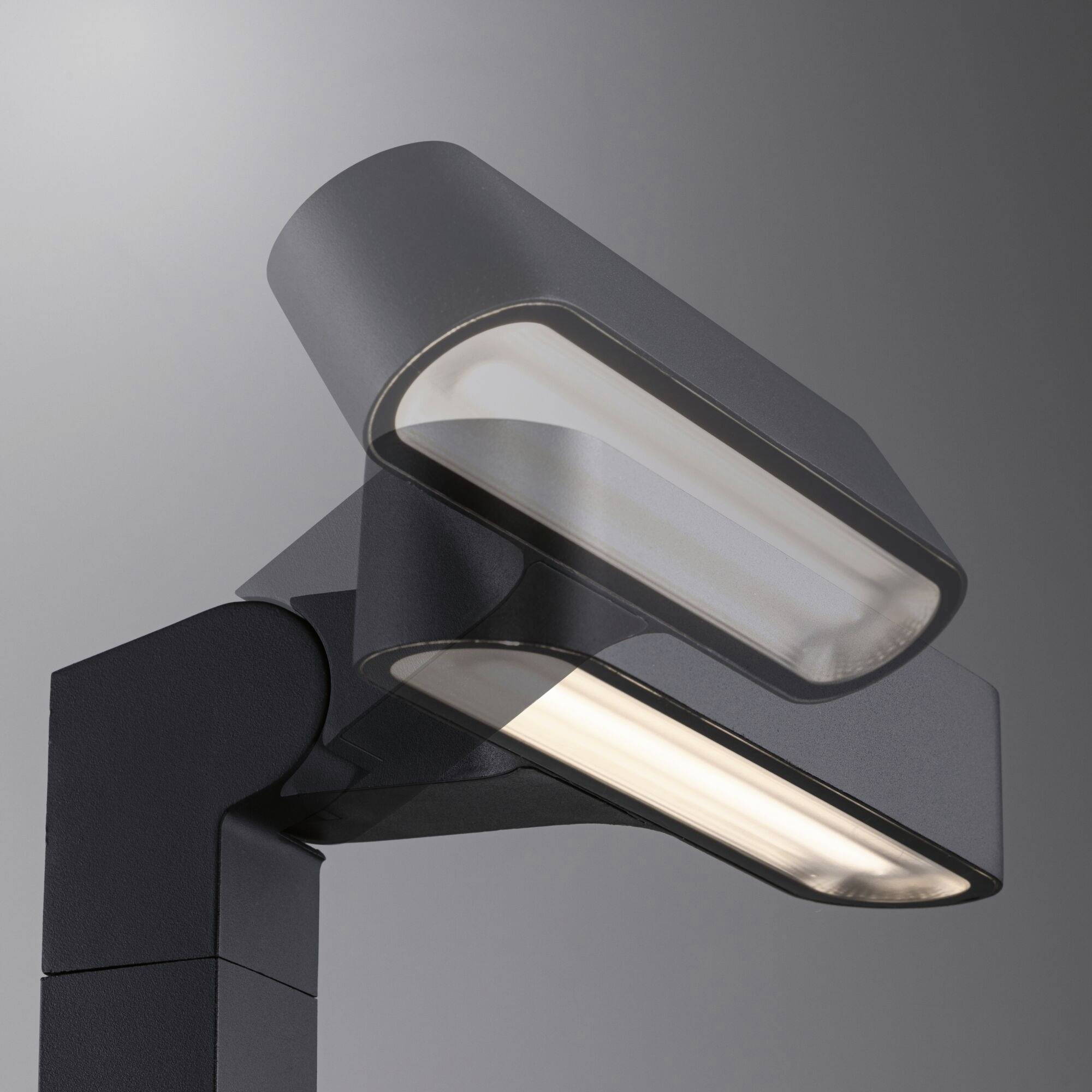 Lampadaire moderne avec deux luminaires rectangulaires légèrement inclinés et disposés l'un au-dessus de l'autre, sur un fond gris-bleu.