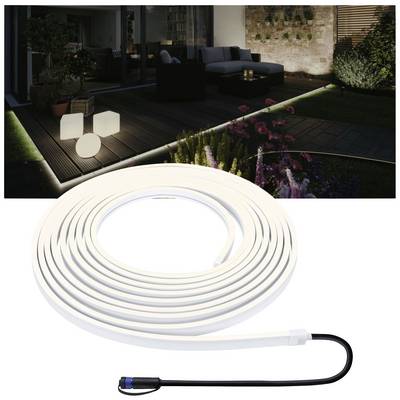 Un jardin éclairé avec des meubles modernes la nuit. Au premier plan, un ruban LED enroulé avec son câble de connexion.