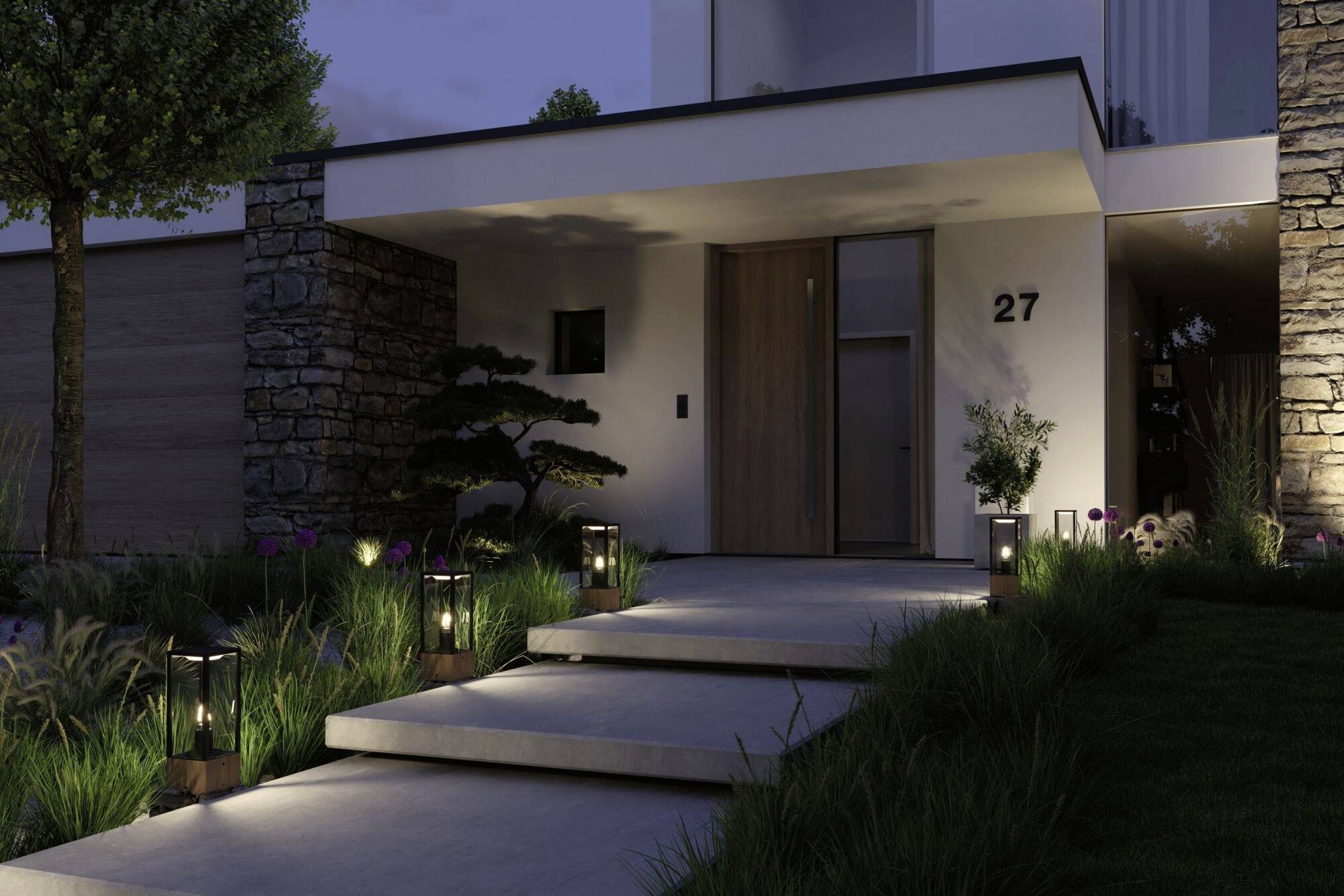 Entrée d'une maison moderne la nuit. Des marches éclairées mènent à la porte d'entrée, entourées de plantes et de murs de pierre.