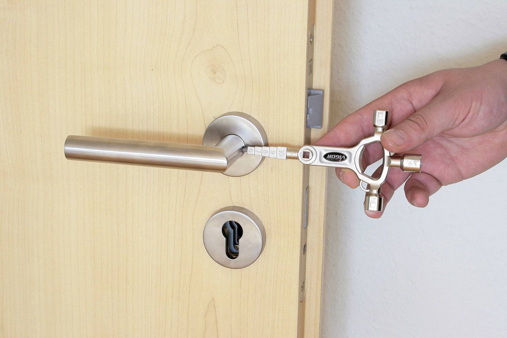 Une main tient une clé à quatre pans et l'insère dans une porte avec une poignée argentée pour la déverrouiller.