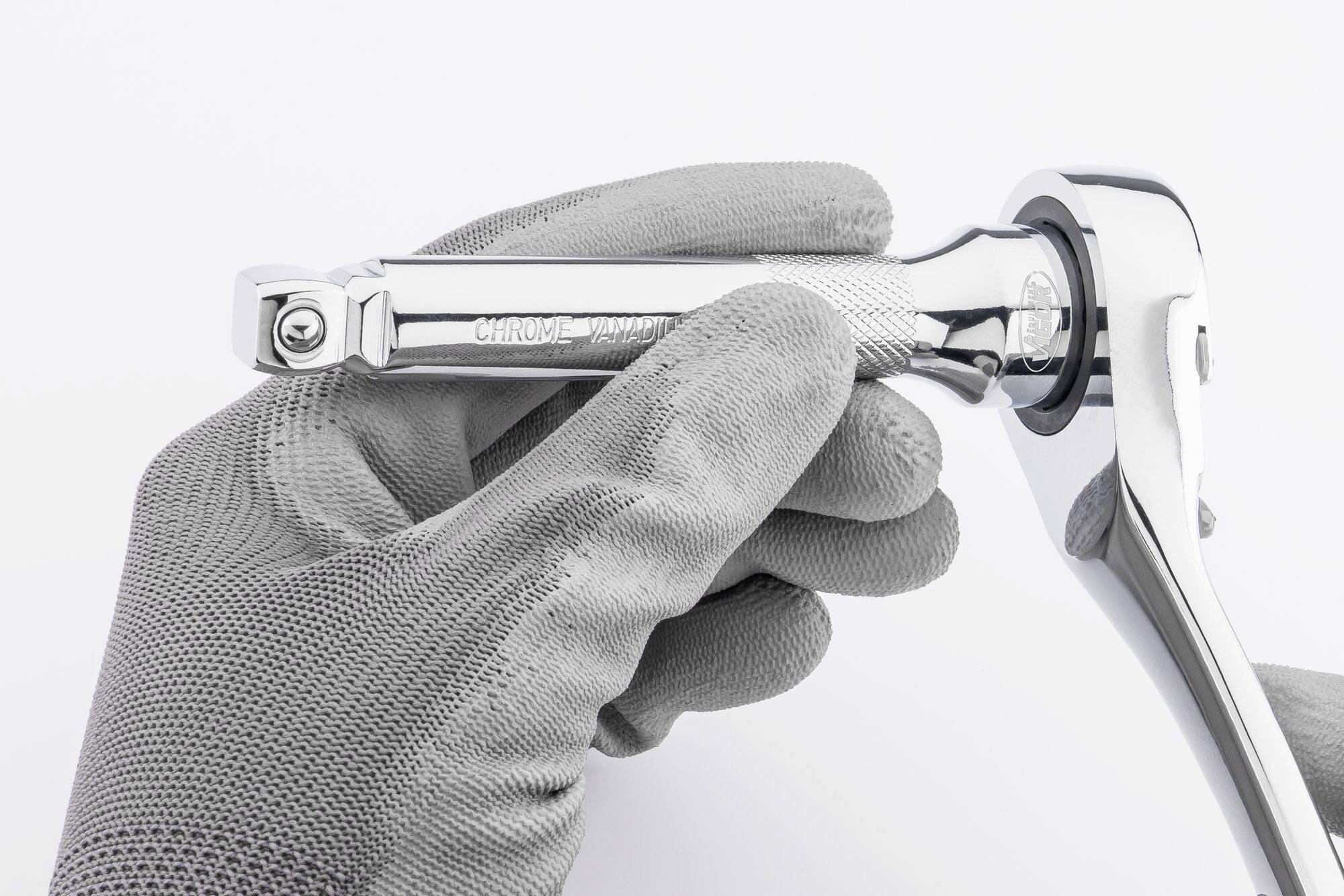 Une main tient une clé à cliquet chromée avec une gravure 'CHROME' sur un fond blanc.