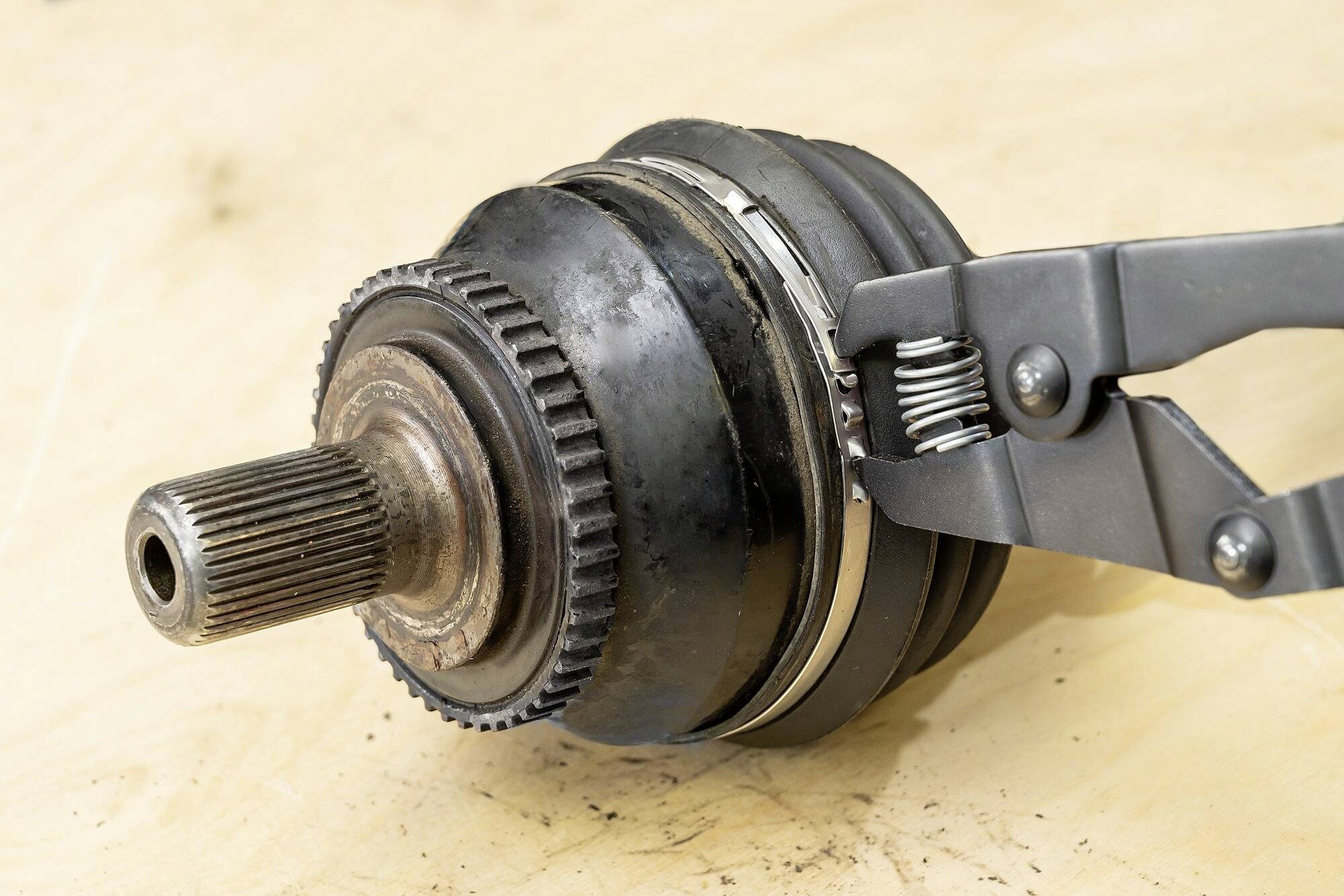 Gros plan d'un joint de transmission extérieur avec une pince retirant une manchette endommagée.
