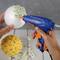 Une personne utilise un pistolet à colle chaude pour coller de petites fleurs sur une boule décorative. Une boule terminée est posée à côté.