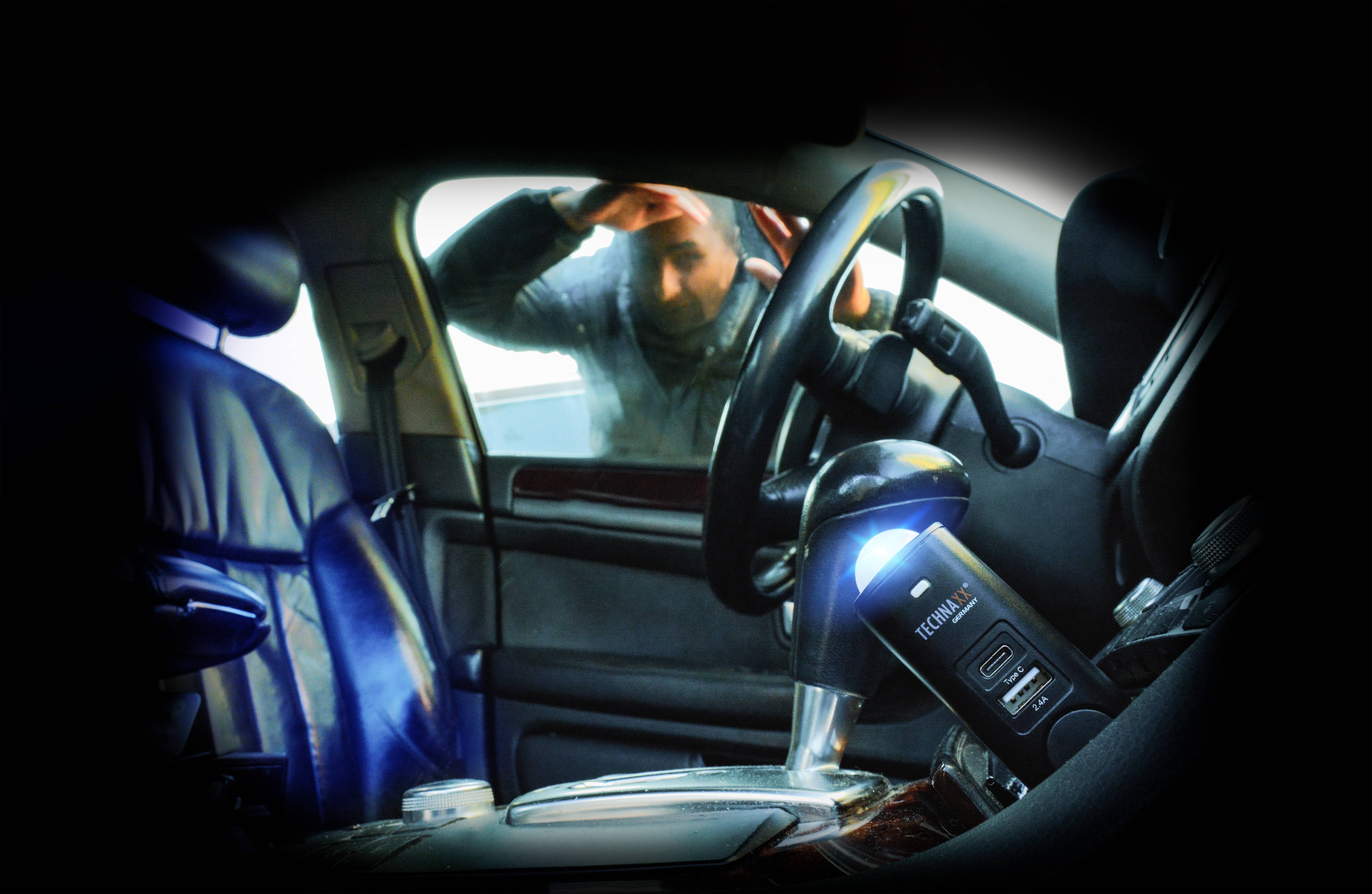 Une personne regarde à l'intérieur d'une voiture de l'extérieur, à travers la vitre latérale fermée. L'habitacle est vide, à l'exception d'un éthylotest posé sur le siège du conducteur.