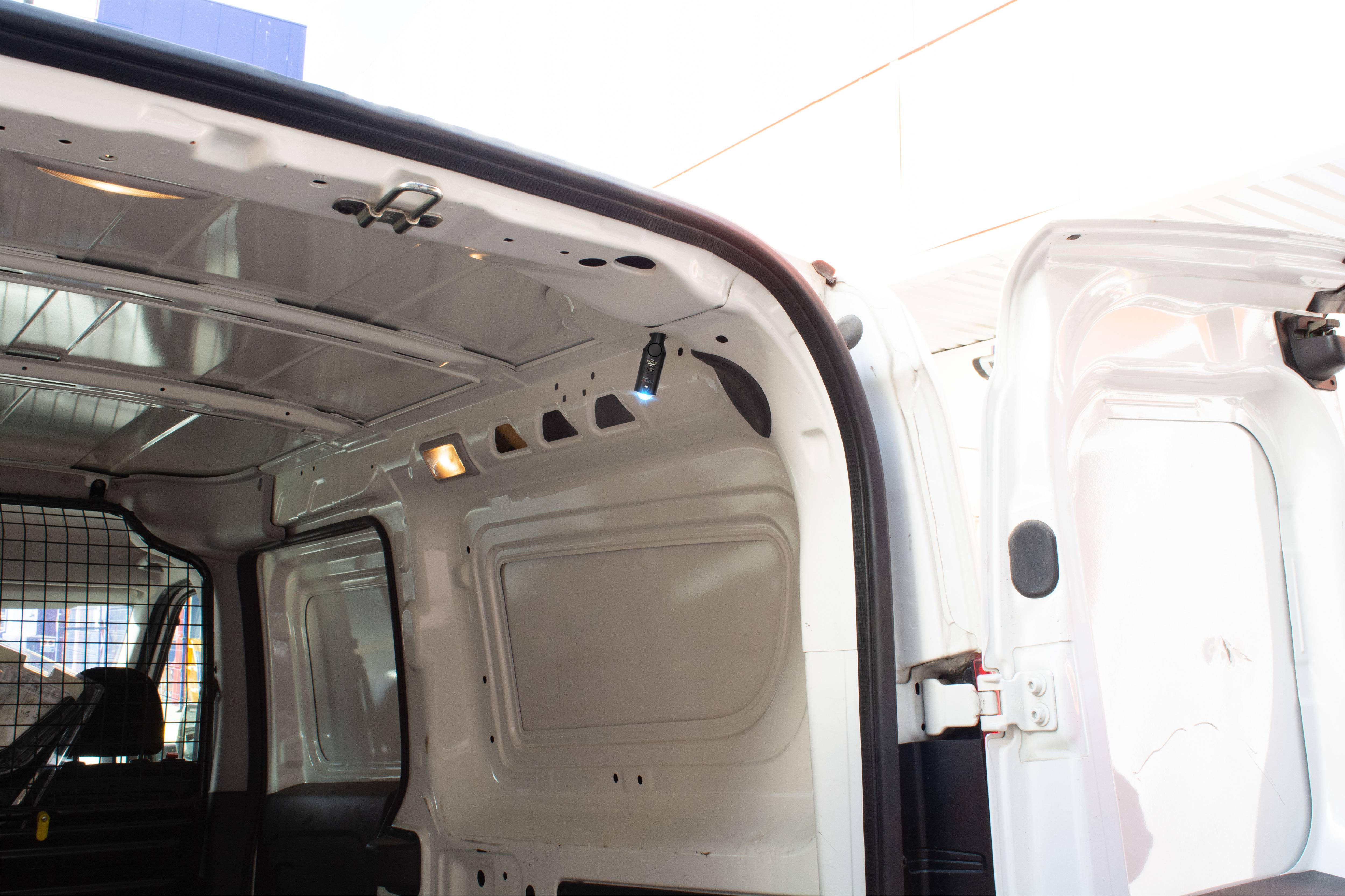 L'espace de chargement ouvert d'une camionnette blanche, éclairé par la lumière du jour. Les portes sont grandes ouvertes et révèlent l'intérieur.