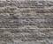 Un mur de briques grises et brunes aux motifs irréguliers, qui paraît rustique et structuré.