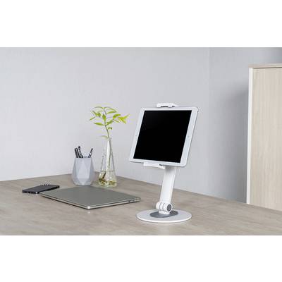 Un bureau avec une tablette sur un support, un ordinateur portable, un smartphone et un porte-stylos décoré avec une plante.