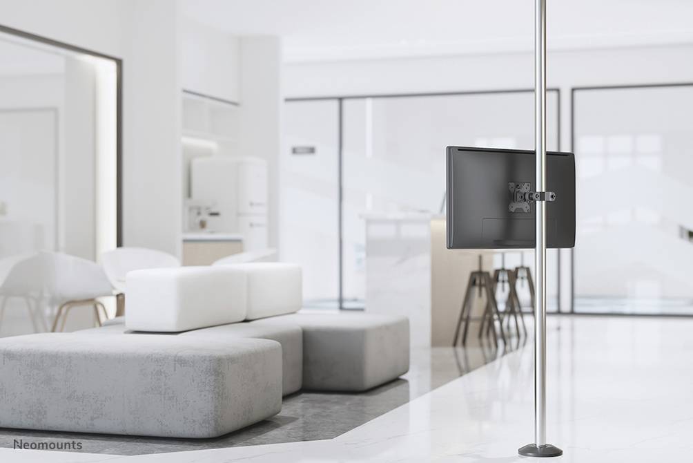 Un espace moderne et lumineux avec des meubles blancs et un canapé gris. À droite de l'image, un écran plat est posé sur un support haut.