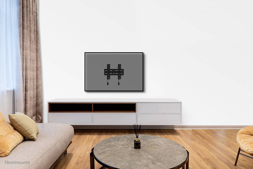 Télévision plate accrochée au mur dans un salon moderne avec canapé, table et tapis.