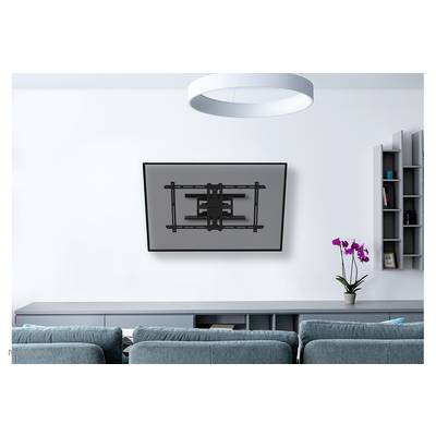 Un téléviseur plat est accroché au mur dans un salon moderne. Au premier plan, un canapé gris, à côté duquel se trouve une orchidée.