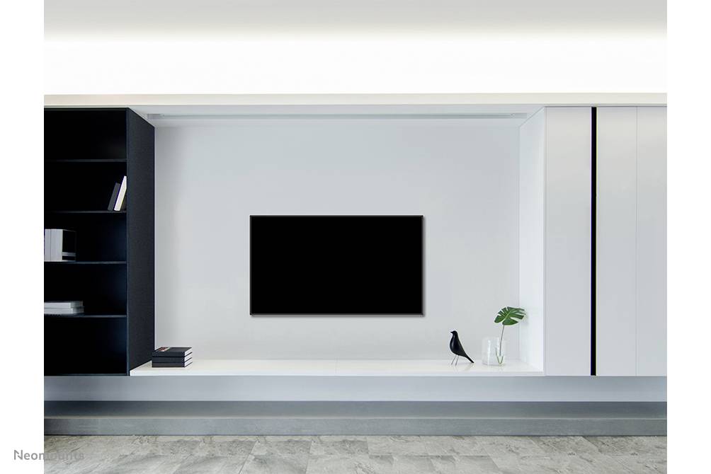 Salon minimaliste avec une étagère murale, un téléviseur et des décorations ; posés dessus, un oiseau et un vase contenant des plantes.