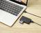 Un ordinateur portable est posé sur une table en bois et connecté à un lecteur de carte via un câble USB. Une carte SD est insérée dans le lecteur.