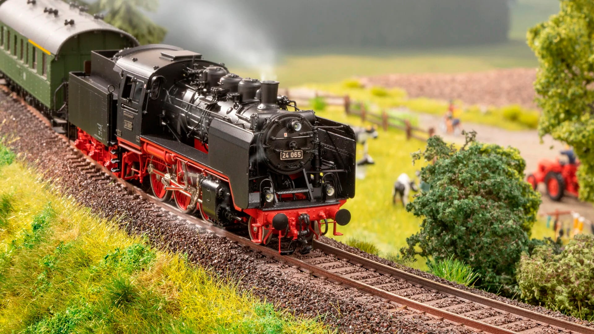 Scène de train miniature avec une locomotive à vapeur circulant sur une voie ferrée, entourée de paysage verdoyant et d'arbres.