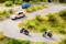 Un paysage miniature montre une route sinueuse avec deux motos et une voiture. Des personnes sont visibles sur les motos.