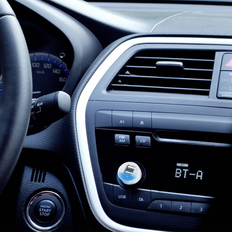 Un tableau de bord de véhicule avec volant, compteur de vitesse et affichage radio. Le bouton de démarrage est visible en dessous de la radio.