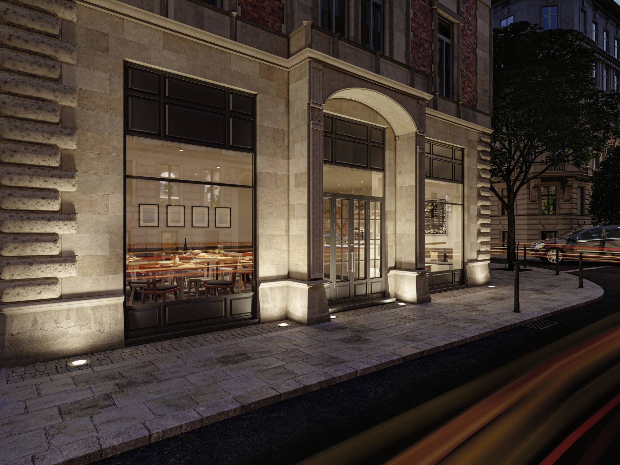 Vue de rue d'un restaurant illuminé dans un bâtiment en pierre la nuit. De grandes fenêtres révèlent un intérieur élégant.